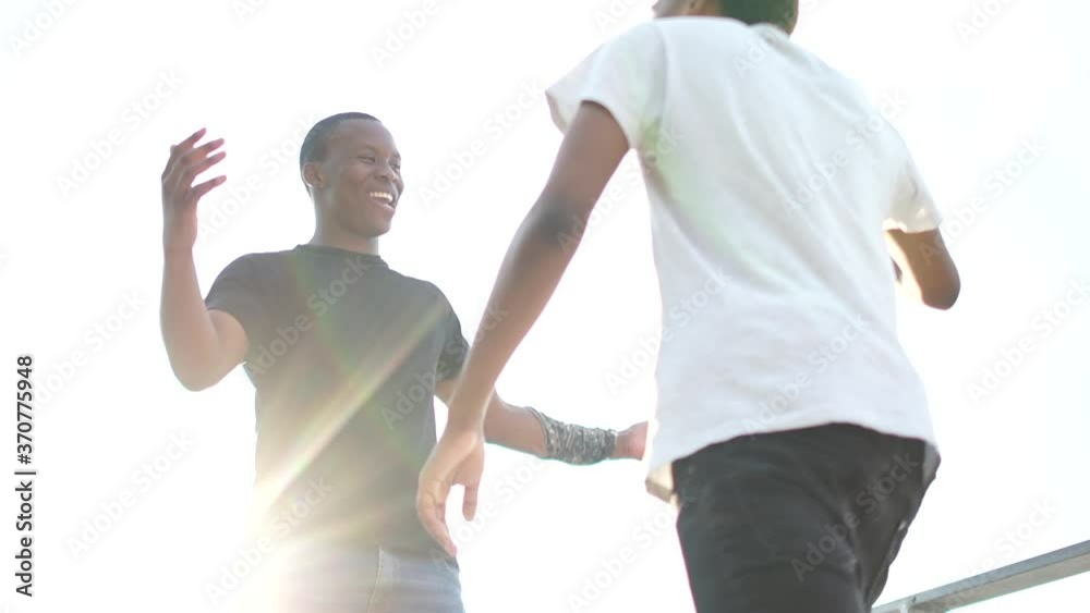 Meeting of two African American men friends. Greeting handshake and hug. Outdoor portret of two black students. Equality and brotherhood concept Meeting of two African American men friends. Greeting handshake and hug. Outdoor portret of two black students. Equality and brotherhood concept