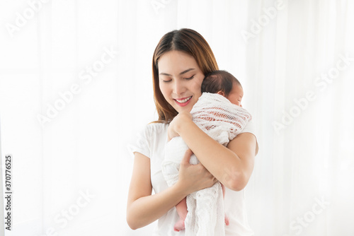 Free Download Pretty asian woman holding a newborn baby in her arms. Happy family. Laughing mother lifting her adorable infant baby son on white.  - GFXLoad