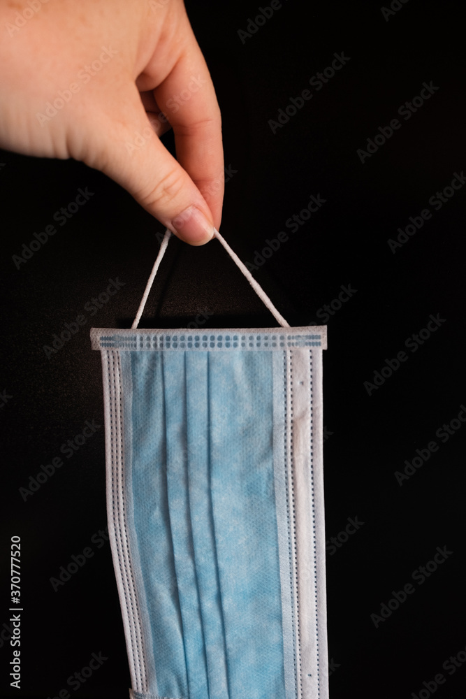 Facial medical mask on black background. Protection against coronavirus, flu and other airborne infections Facial medical mask on black background. Protection against coronavirus, flu and other airborne infections