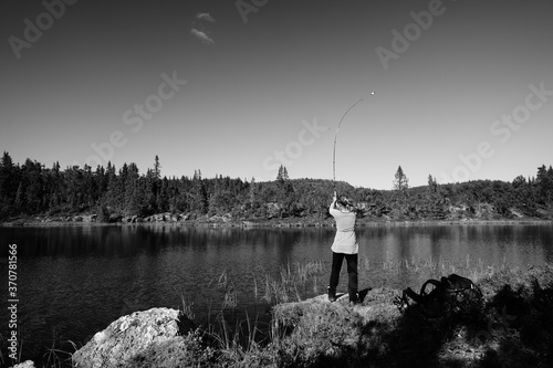 A young girl fishes in a small lake in the wild nature of Norway, Hallingdal, Gol. Shot in black and white. photo