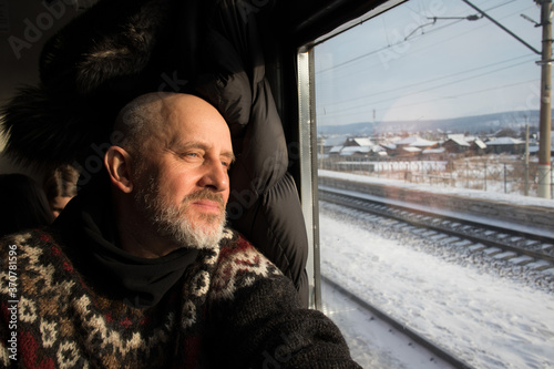 Mann sitzt im Zug und schaut aus dem Fenster auf die  russische Winterlandschaft photo