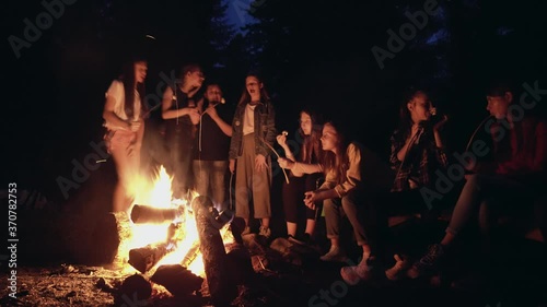Teens roasting marshmallows on campfire.