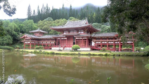 Buddhist temple in the Valley of the Temples Cemetary in Oahu, Hawaii with jumping fish in the pond.