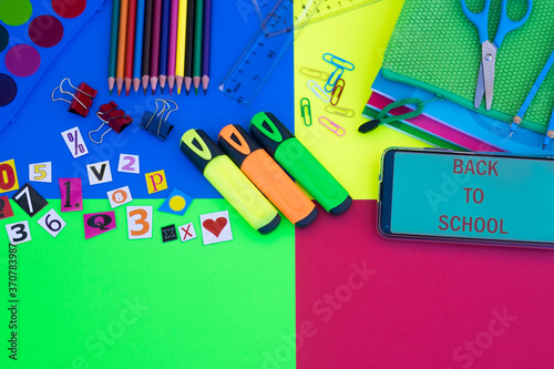 Group of items for back to school on colorful background, pencils, notebooks, scissors elements and text on smart phone - education concept