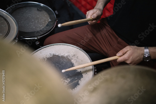 Side view of cropped drummer playing drums with sticks. Close-up view of man s hands holding wooden sticks over drums in music studio.