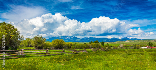 Montana Big Sky Landscape of a ranch fence with clouds and mountains in the background