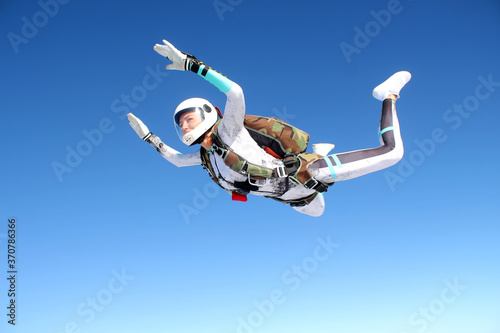 Skydiving. A happy girl is flying in the blue sky.