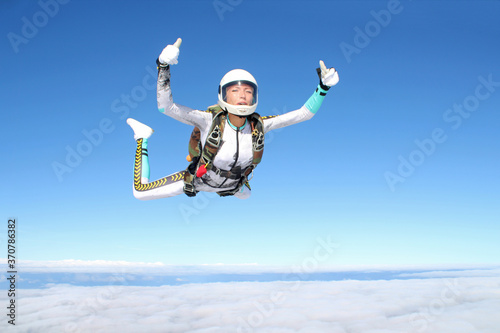Skydiving. A happy girl is flying in the blue sky.