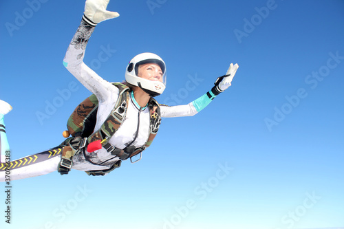 Skydiving. A happy girl is flying in the blue sky.