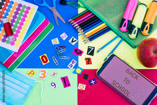 Back to school with surgical mask due to coronavirus - colorful background, pencils, notebooks, scissors, pen drive and accessories - education concept