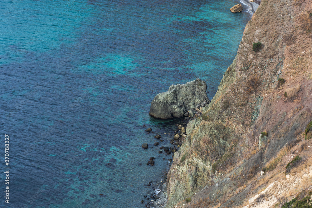 View from the cliff down to the sea. Beautiful turquoise sea water. Rocky coast close-up. The black sea in Crimea. Cape Fiolent Sevastopol.