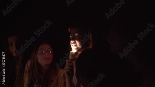 Teenager telling scary story using flashlight on face.