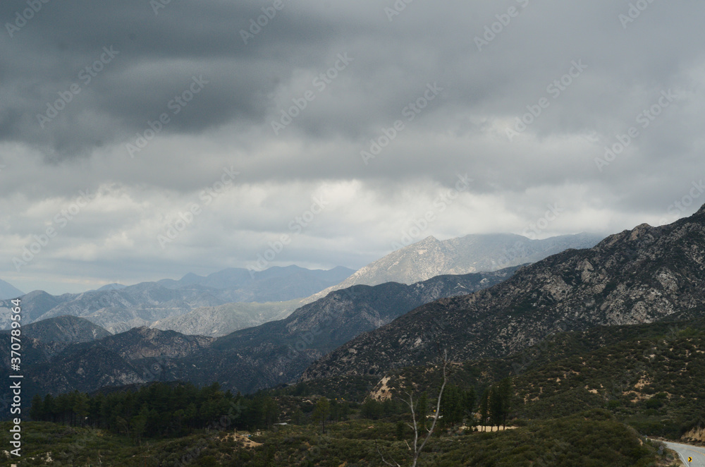 Angeles forest in the mountains with very threatening  clouds of storm type, beautiful landscape of mountain ranges, valley, clouds and wonder vista of light and shadow, conveys beauty, danger, 