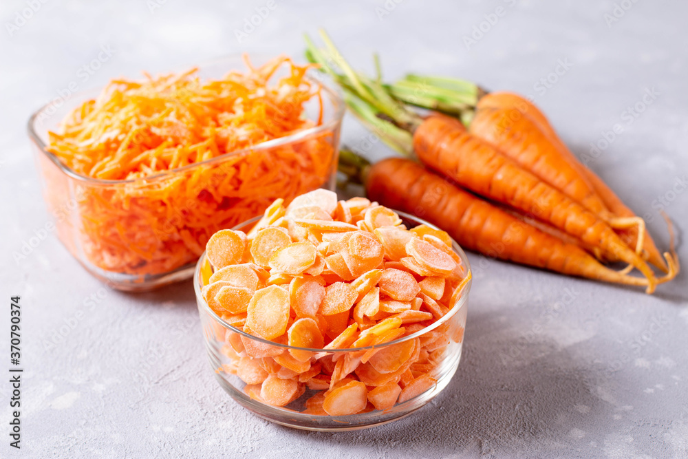 Frozen carrots in different ways in a glass container on a light background Frozen carrots in different ways in a glass container on a light background