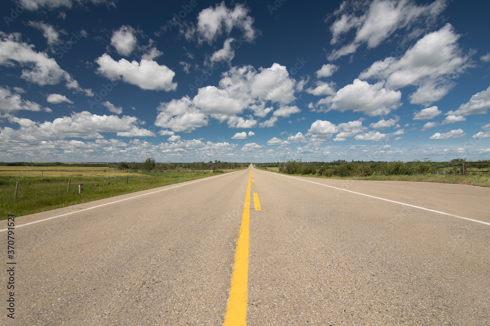 A scenic route along a prairie Highway in Northern Alberta under a deep blue sky.