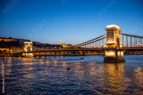 The Szechenyi Chain Bridge crossing the Danube river and St. Matthias Church at dusk, Budapest, Hungary