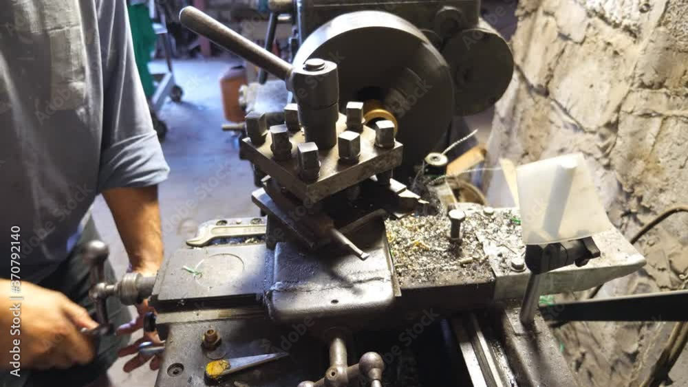 Close up or milling machine in action. Unrecognizable turner working with old workbench in his garage or workshop. Mechanic using lathe for metal processing. Slow motion