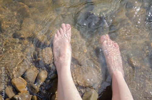 Female feet in the water. Water spa treatments. Foot stones river. photo