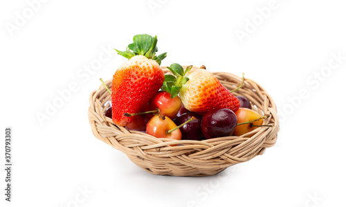 Strawberries, and Cherries in woven basket isolated on white background.
