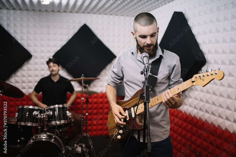 Fototapeta premium Music band with vocalist and guitarist practicing. Rock music band playing in recording music studio.