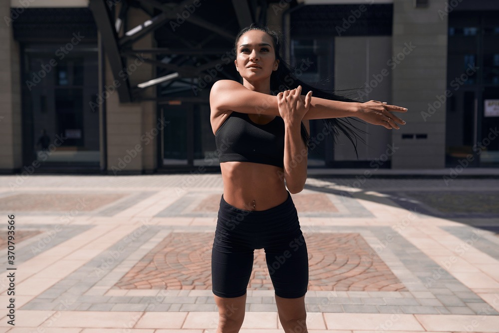 Obraz premium Rear view of woman stretching her arm and shoulder.