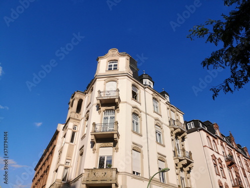 Altes Eckhaus in Beige und Naturfarben mit schönen Balkons vor blauem Himmel im Sommer bei Sonnenschein im Westend von Frankfurt am Main in Hessen photo