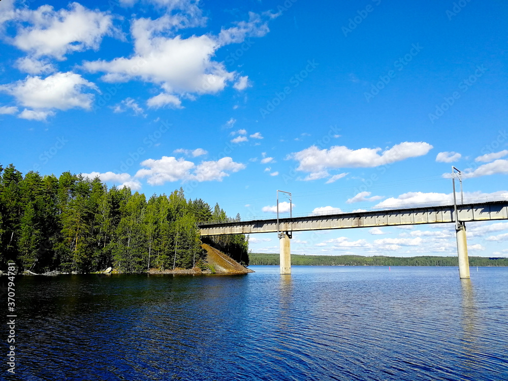 A bridge across the lake strait in Central Finland. Beautiful colorful summer landscape with blue sky and fluffy clouds.