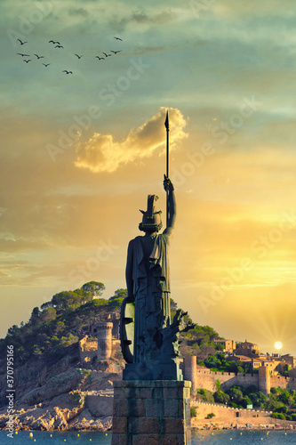 View of the Minerva statue in the foreground by summer sunset, with an out of focus background of Tossa de Mar castle. Costa Brava, Catalonia, Spain