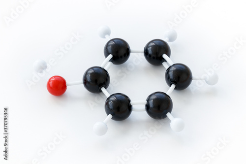 Plastic ball-and-stick model of a phenol molecule (C6H5OH), shown with kekule structure on a white background. photo