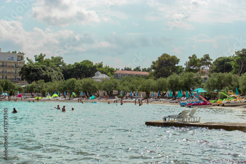 Fototapeta Naklejka Na Ścianę i Meble -  Supetar, Croatia August 2020 Famous beach in the town of Supetar, filled with people swimming on a warm summer day. Tourists travelling even in the time of covid global pandemic