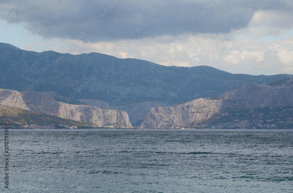 View of the town of Omis in Croatia, seen from the island of Brac from very far away. Two mountains meeting on the point where river flows into the adriatic sea