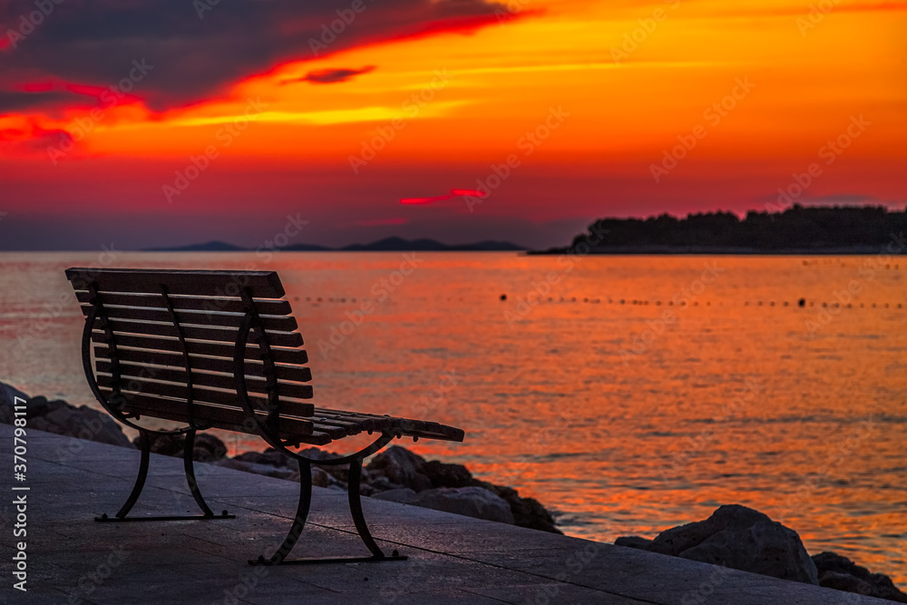 Sea landscape at sunset with bench in Primosten town, a popular tourist destination on the Dalmatian coast of Adriatic sea in Croatia, Europe. Sea landscape at sunset with bench in Primosten town, a popular tourist destination on the Dalmatian coast of Adriatic sea in Croatia, Europe.