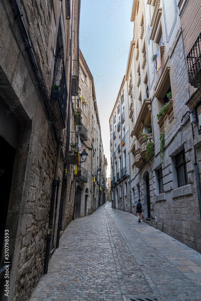 Views of the narrow streets of the old town of Girona with a woman.