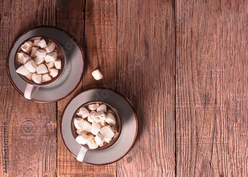 Hot chocolate with cinnamon and marshmallow on wooden background
