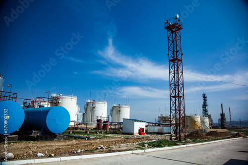 Oil Refinery and gas processing plant. Shiny metal oil storage tanks and blue water storage tank on blue sky with clouds. Black lighting mast on blue sky. Jambyl region, Kazakhstan. photo
