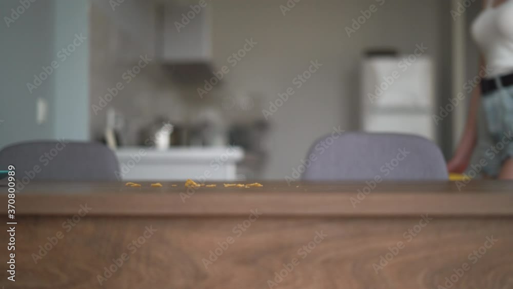 The woman goes to the table and wipes off the remnants of food with a damp napkin. Cleaning up after meals The woman goes to the table and wipes off the remnants of food with a damp napkin. Cleaning up after meals