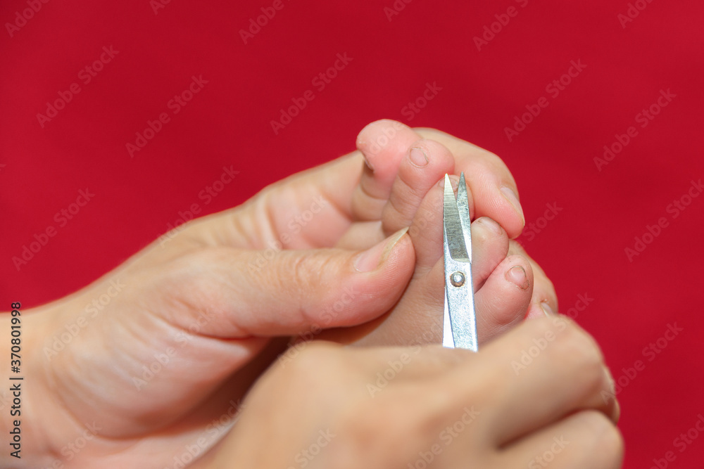 Mom cuts baby's toenails with small baby scissors. Care and guardianship of children by parents. Mom cuts baby's toenails with small baby scissors. Care and guardianship of children by parents.