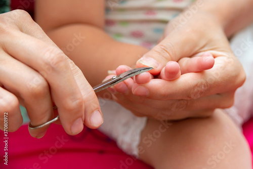 Mom cuts baby's toenails with small baby scissors. Care and guardianship of children by parents.