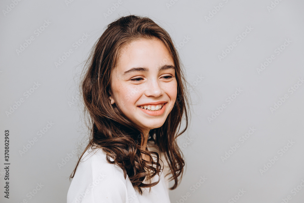 little pretty girl with expressive facial features posing for a photo on a gray background little pretty girl with expressive facial features posing for a photo on a gray background