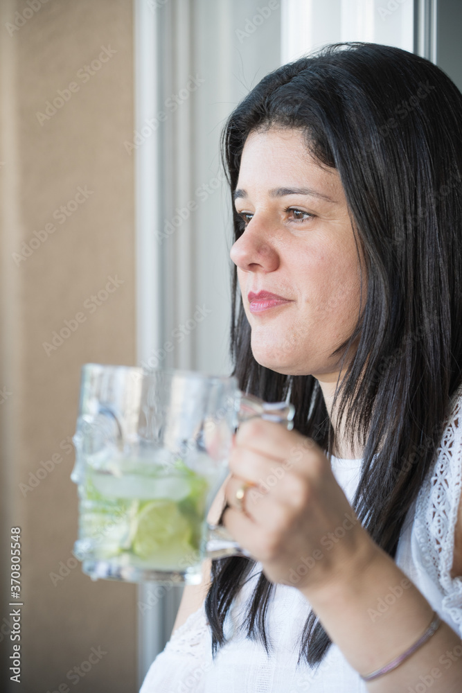 Mulher branca de cabelos negros tomando um drink de caipirinha, bebida brasileira, dentro de uma caneca de vidro. Mulher branca de cabelos negros tomando um drink de caipirinha, bebida brasileira, dentro de uma caneca de vidro.