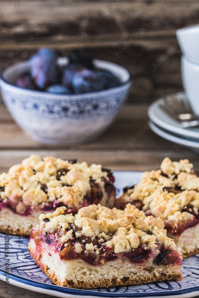 Three pieces of plum cake with crumble on a bluewhite plate on a wooden table Three pieces of plum cake with crumble on a bluewhite plate on a wooden table