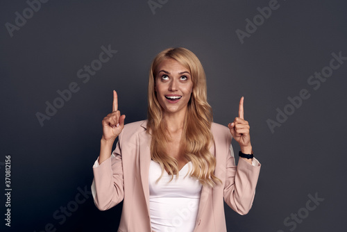 Portrait of positive cheerful business lady point index finger copy space present ads  recommend select suggest wear good look clothes isolated over grey color background