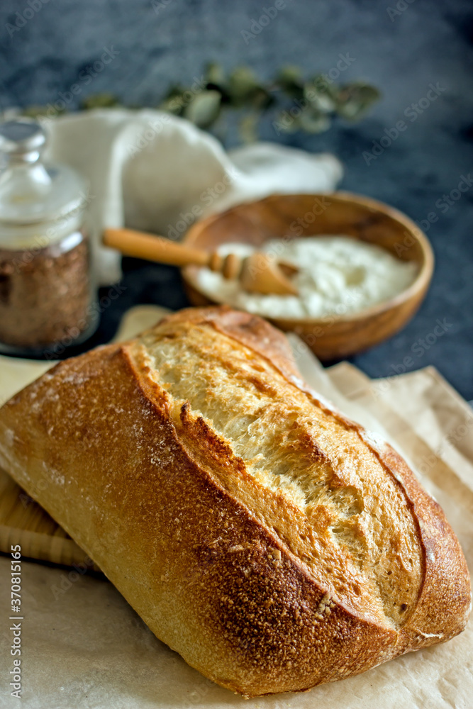 Homemade sourdough bread on a dark table with a napkin, next to flour. Loaf of freshly baked bread close up, vertical background