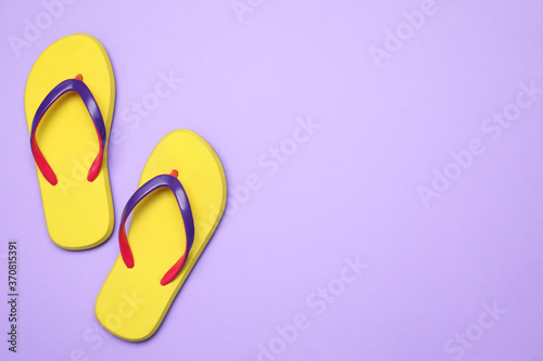 Pair of stylish flip flops on violet background, top view with space for text. Beach objects
