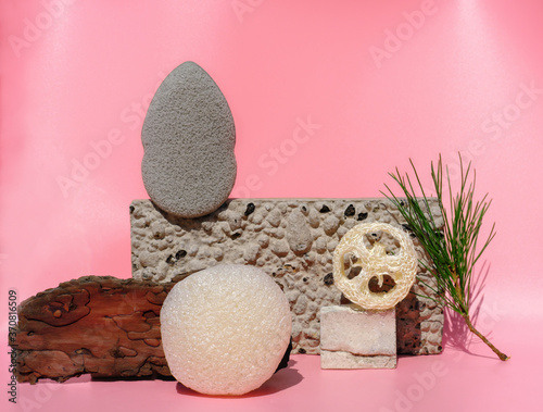 variety of cleansing sponges on natural stone podiums. konjac and loofahs sponges, face cleaning sponges on trendy pink background. home face care routine concept. natural eco beauty products. photo