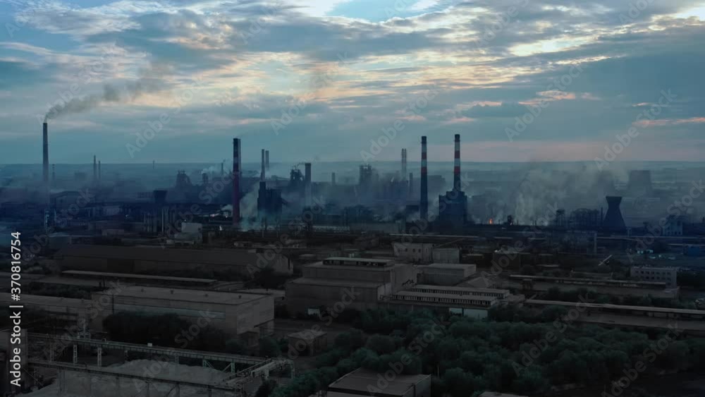 Drone shot of industrial zone with thick smog and burning fossil fuels. Factory zone pan shot right to left of polluted city, many factory chimneys in city area, water line Drone shot of industrial zone with thick smog and burning fossil fuels. Factory zone pan shot right to left of polluted city, many factory chimneys in city area, water line
