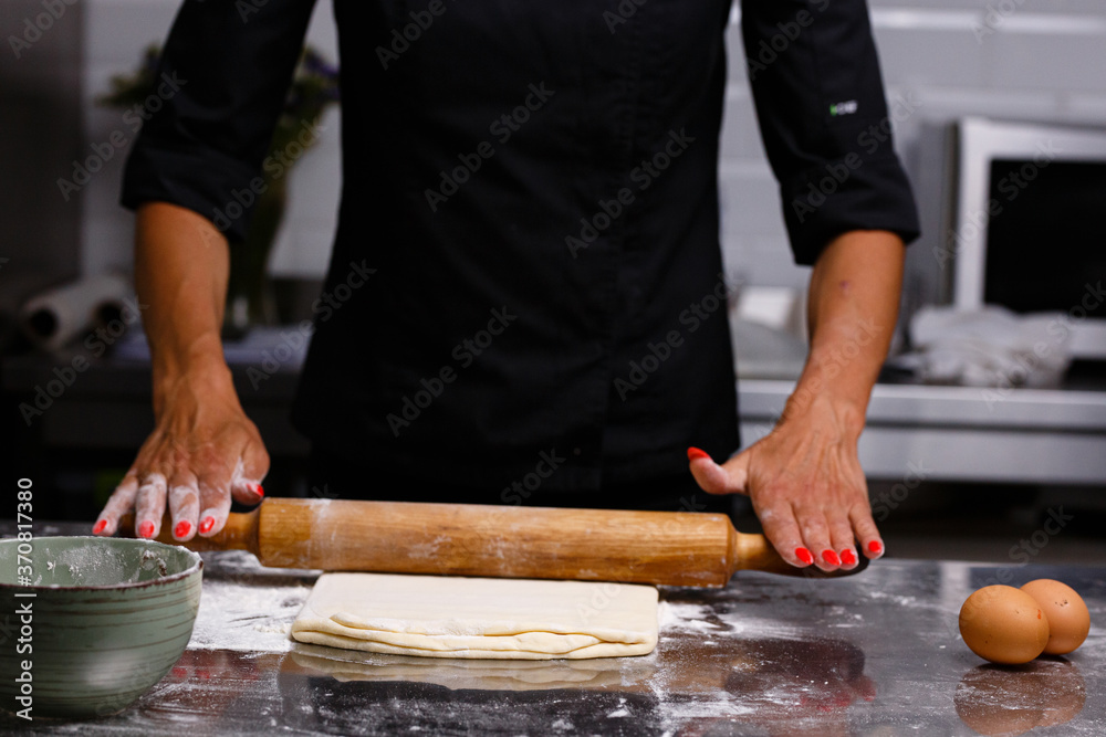 The chef prepares pastries in a professional kitchen. Dark background.