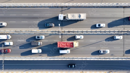 Aerial view of a two-lane expressway or two-lane bridge freeway at the sunset. Vehicles and commercial trucks can be seen.