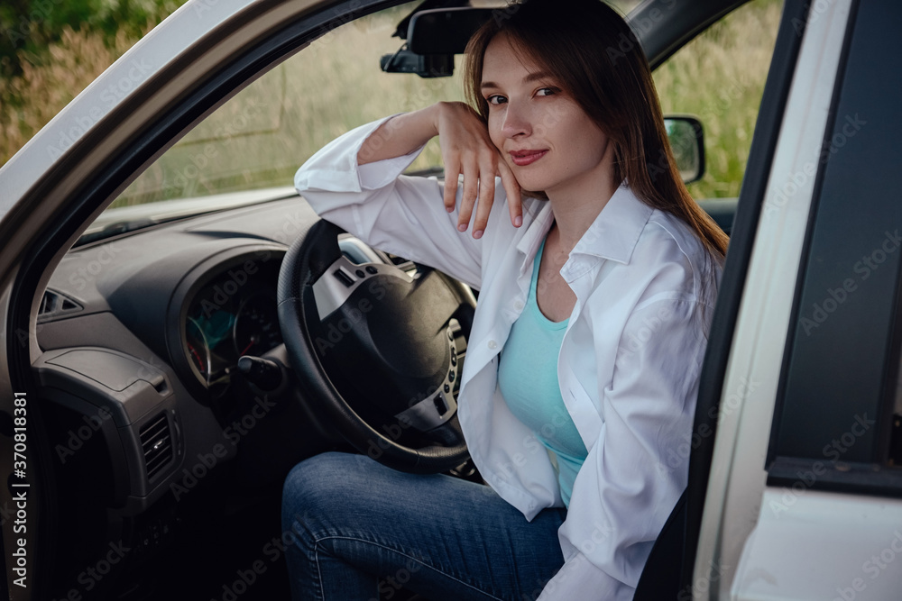 a beautiful young woman driving a grey car.
