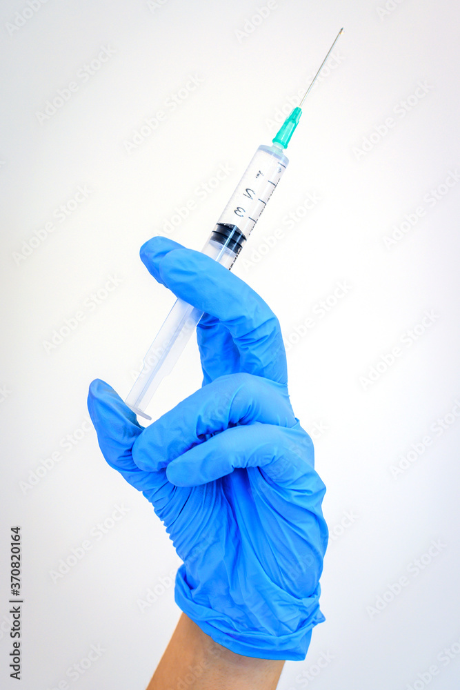 Doctor holding syringe in blue gloves Doctor holding syringe in blue gloves